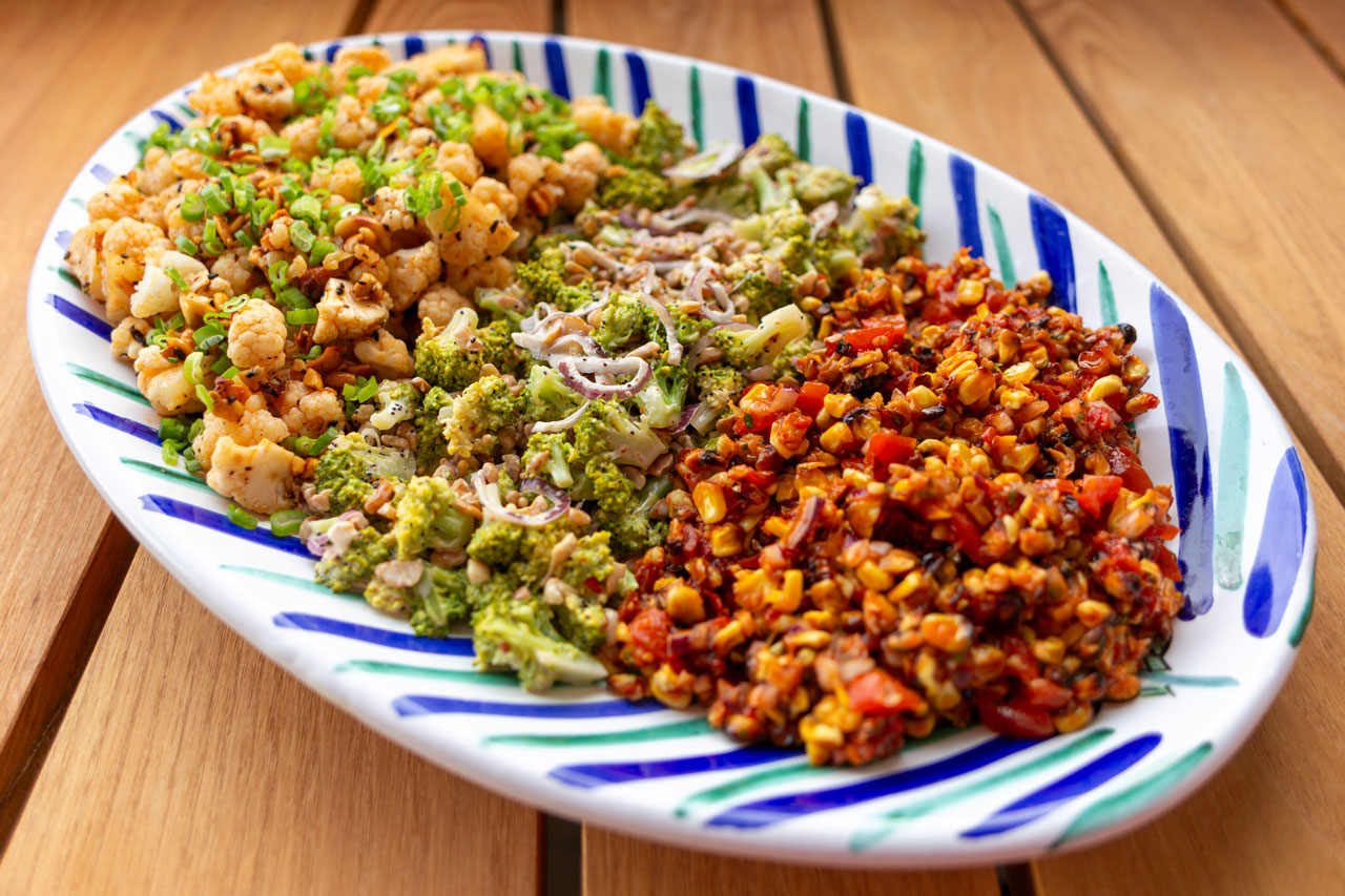 Bunte Salate auf ovalem Teller auf Holztisch Flamboyant Food Fotografie