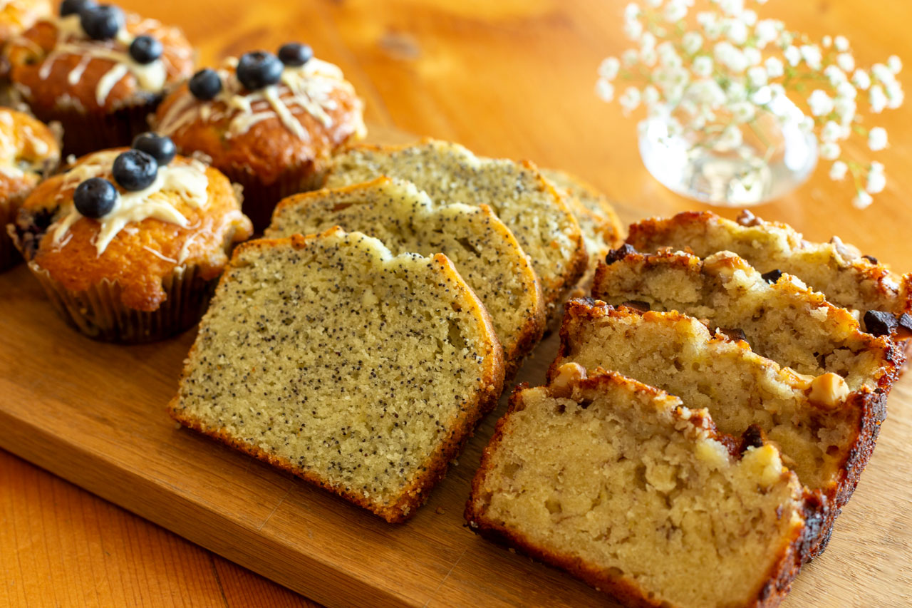 Kuchen & Muffins auf Holzbrett mit Blumen im Hintergrund Flamboyant Food Fotografie